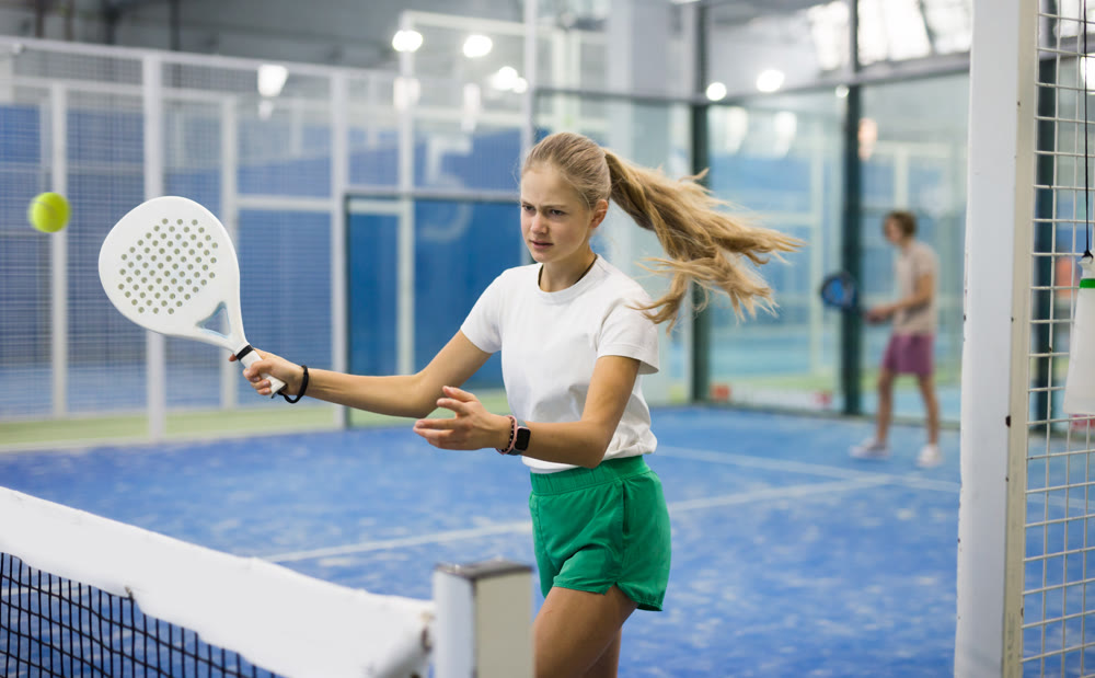 Teenage girl playing padel game on court
