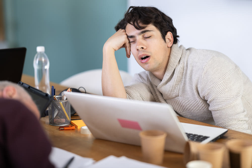 Tired elderly and young male colleagues fall asleep while working