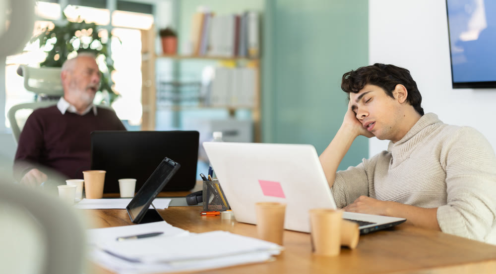 Tired male office workers having nap while sitting in workplace