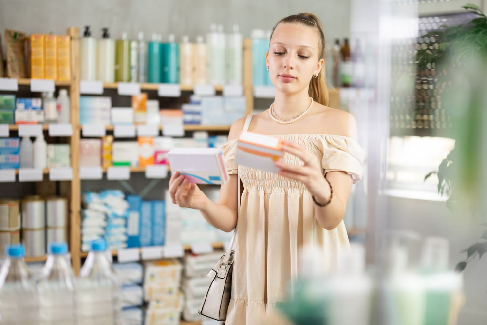 Girl in summer clothes looking for medicine in pharmacy