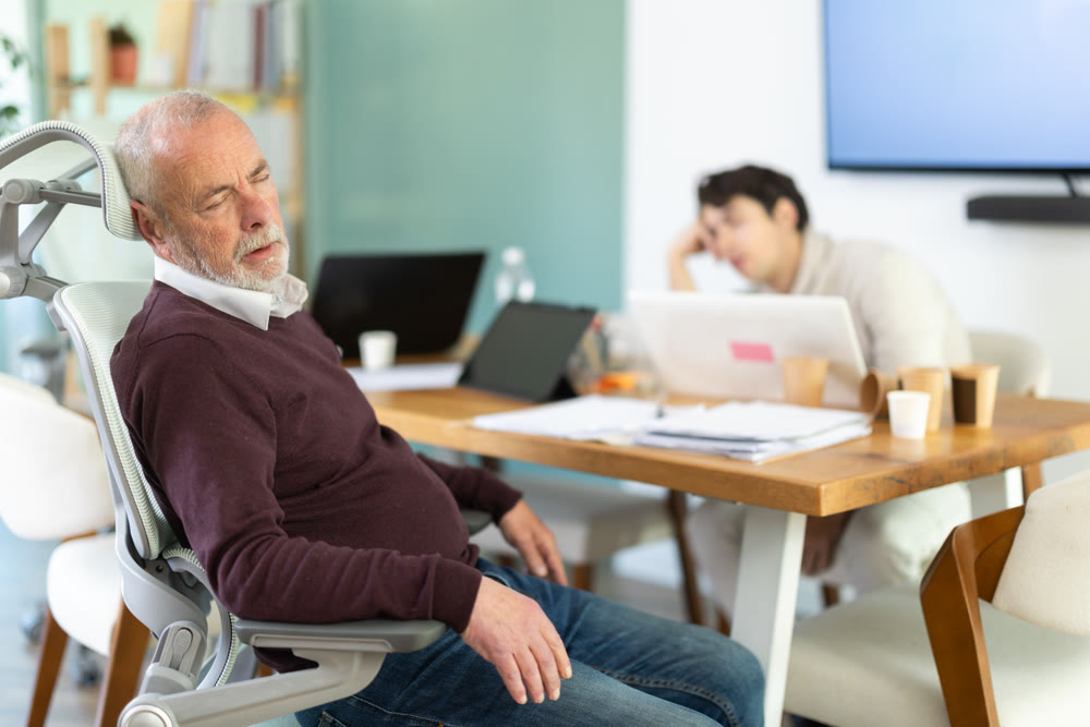 Tired male office workers having nap while sitting in workplace