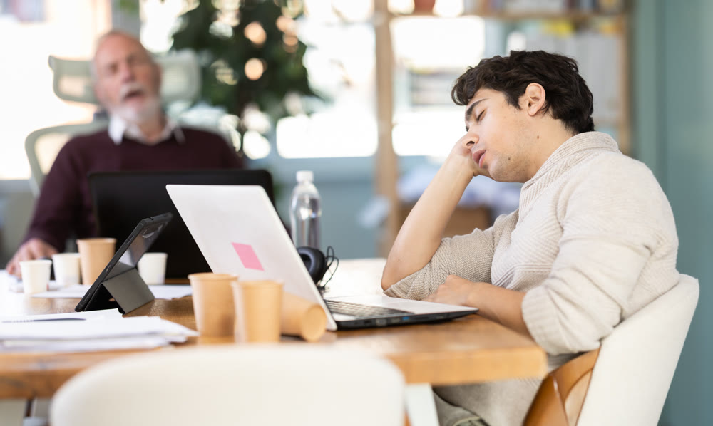Wearied senior man and guy colleagues are dozing near workplace in office