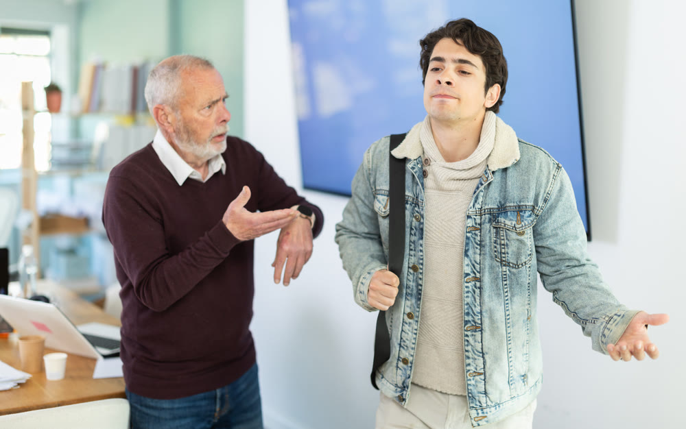 Mature boss scolds an male employee for being late for work