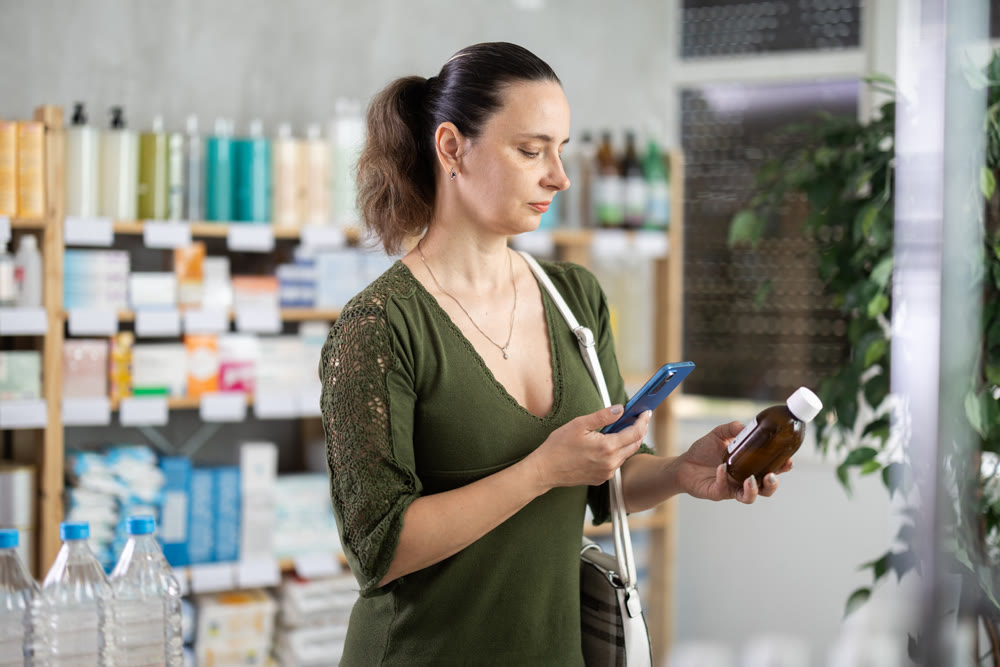 Middle-aged woman customer choosing syrup in drugstore