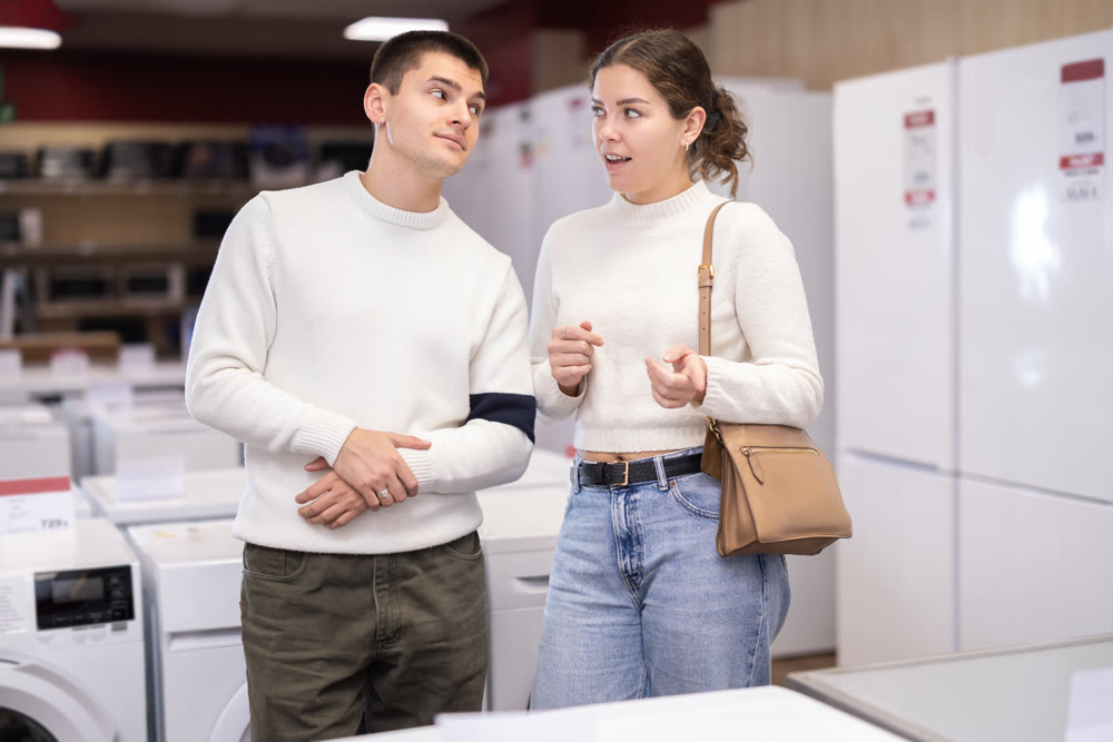 Young couple choosing washing machine or dishwasher