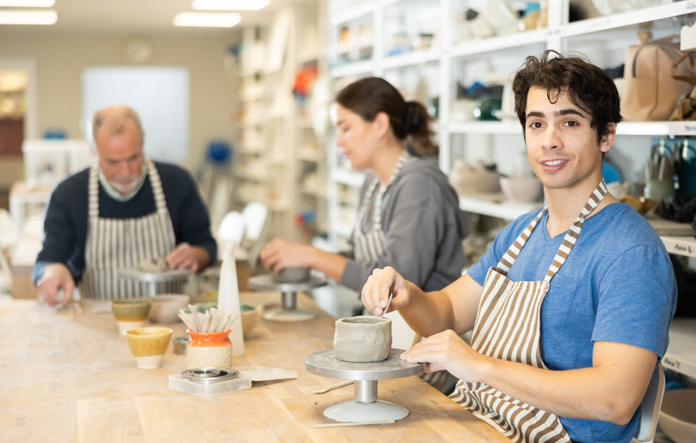 Young man sculpts ceramic piece in workshop
