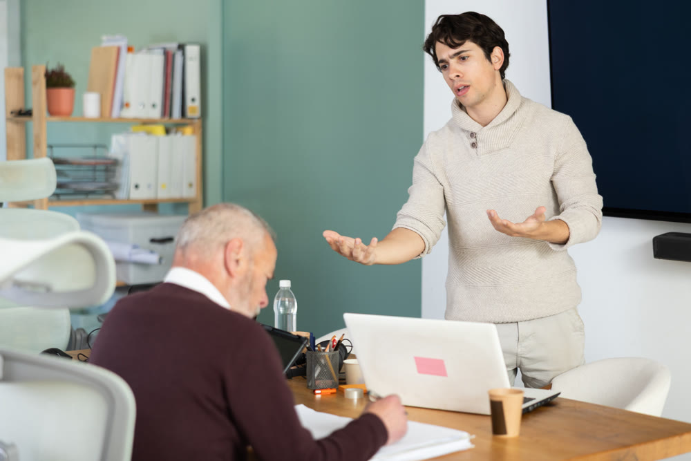 Guy head of department shouts at senior man subordinate who is working with documents