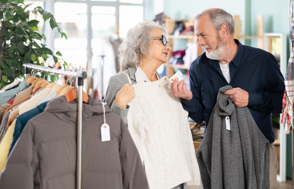 Elderly married couple chooses fashionable sweater in clothing store