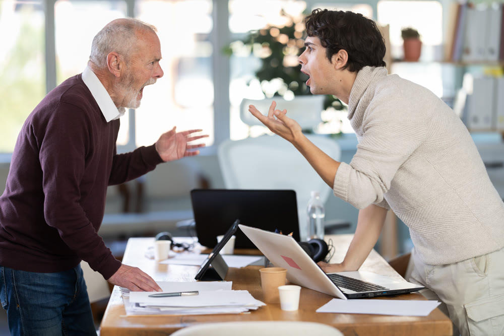 Elderly and young men arguing loudly in office