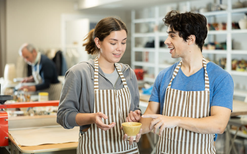 Young man showing ceramic piece to woman