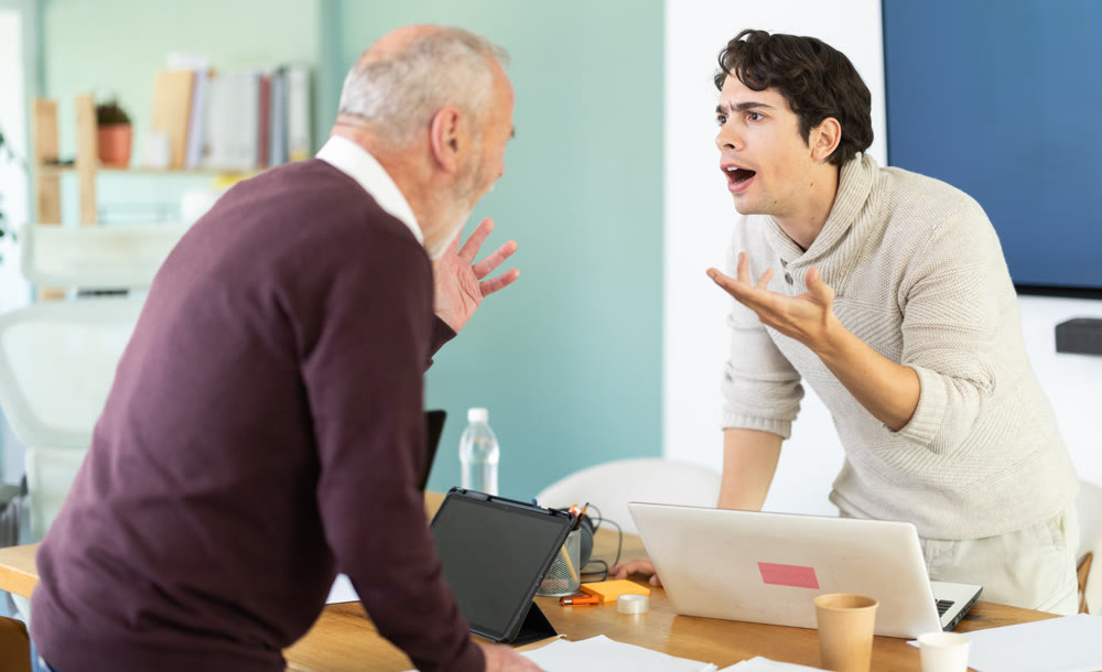 Elderly and young men arguing loudly in office