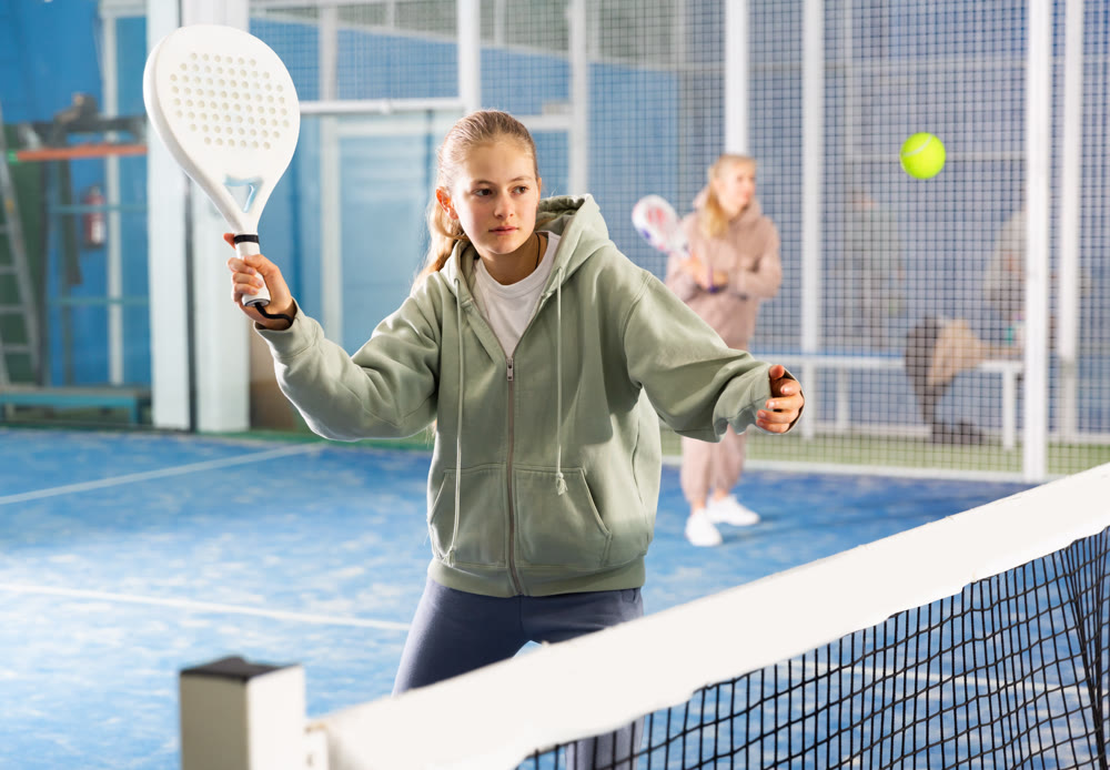 Padel game - teen girl actively kicks ball during a padel game