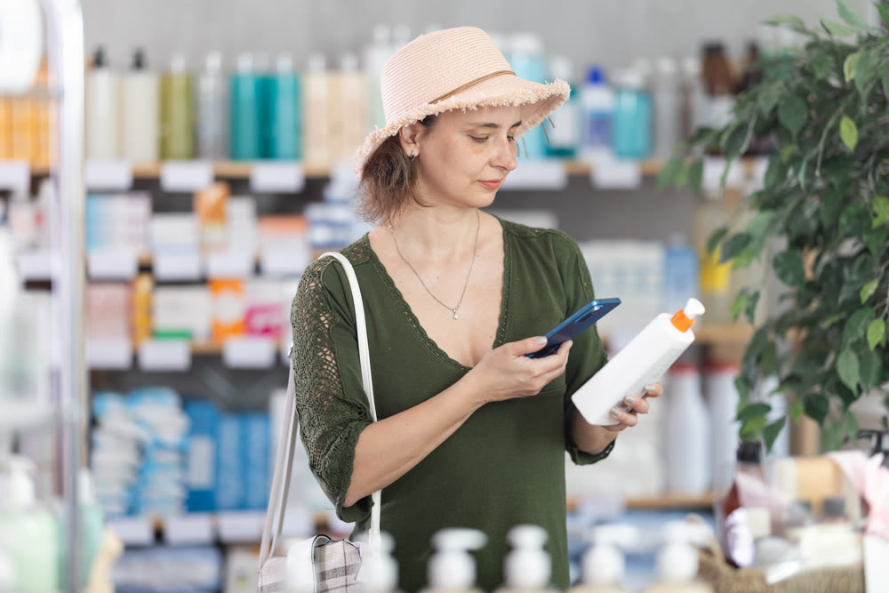 Woman scanning the barcode of a package with SPF cream in a pharmacy