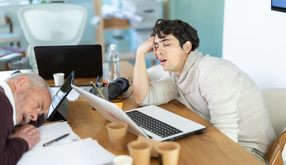 Tired male office workers having nap while sitting in workplace