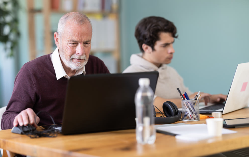 Two male manager work on laptops in modern company office