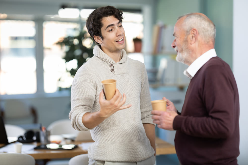 Young and elderly men colleagues drinking coffee in office