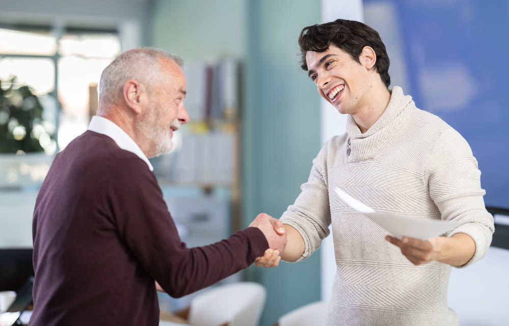 Smiling senior man makes deal, shaking hands with guy