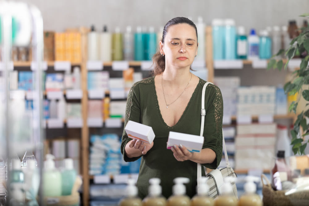 Middle-aged woman customer choosing pills in box in drugstore