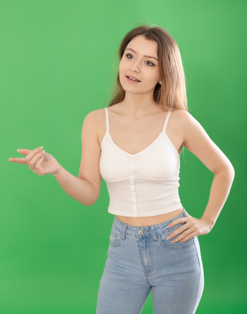 European woman stands on a green background and says