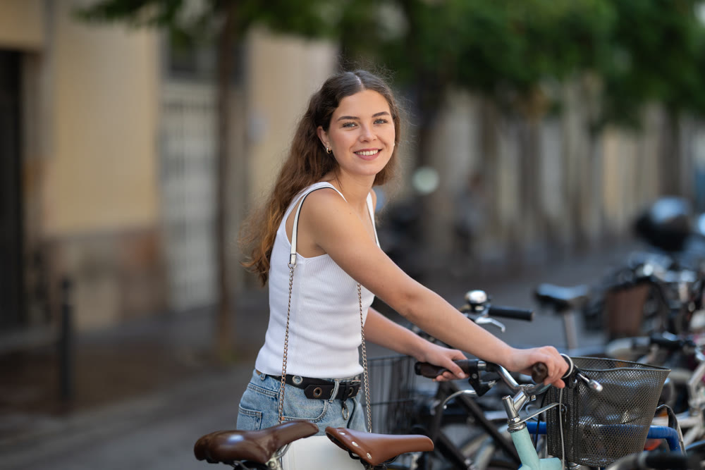 Young girl parks her bicycle on street after walking around city