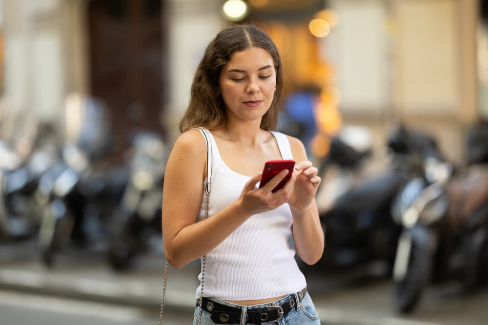 Girl looks at smartphone screen while walking