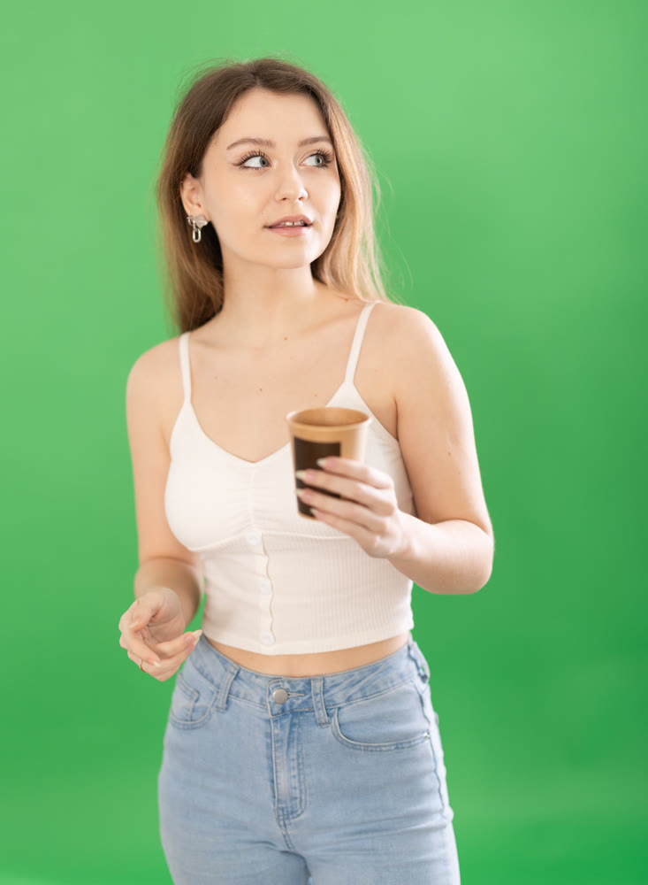 European woman enjoying coffee on a green background