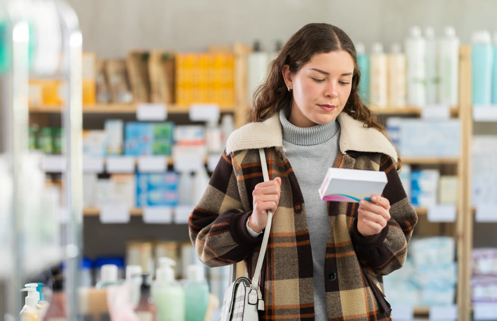 Girl in winter clothes looking for medicine in pharmacy