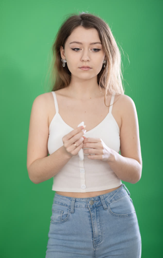 Sad young woman crying in front of green screen