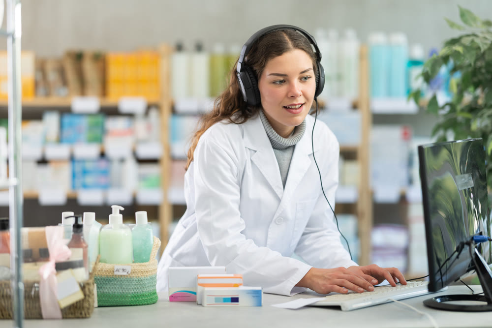 Female pharmacist in headphones working at computer