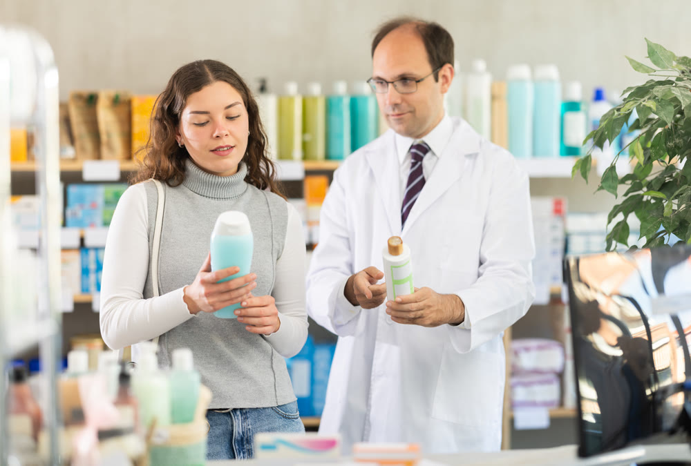 Woman choosing shampoo with help of pharmacist