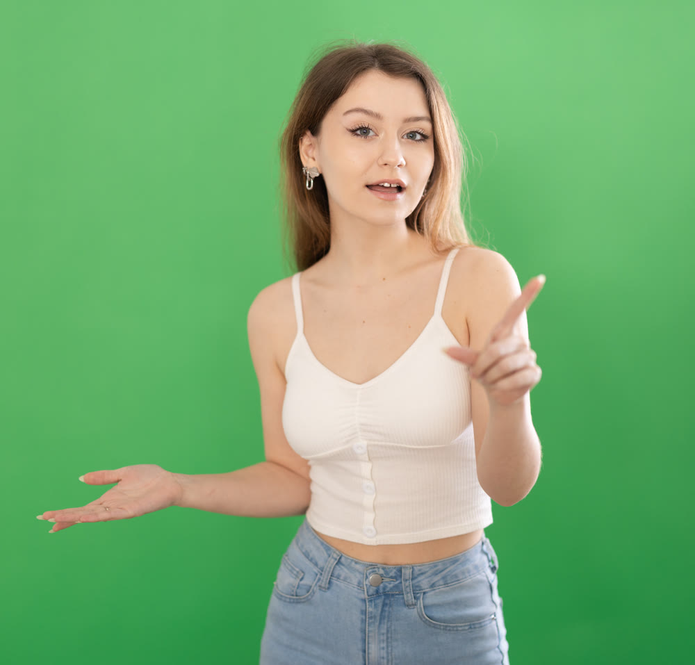Young woman talking in front of green screen