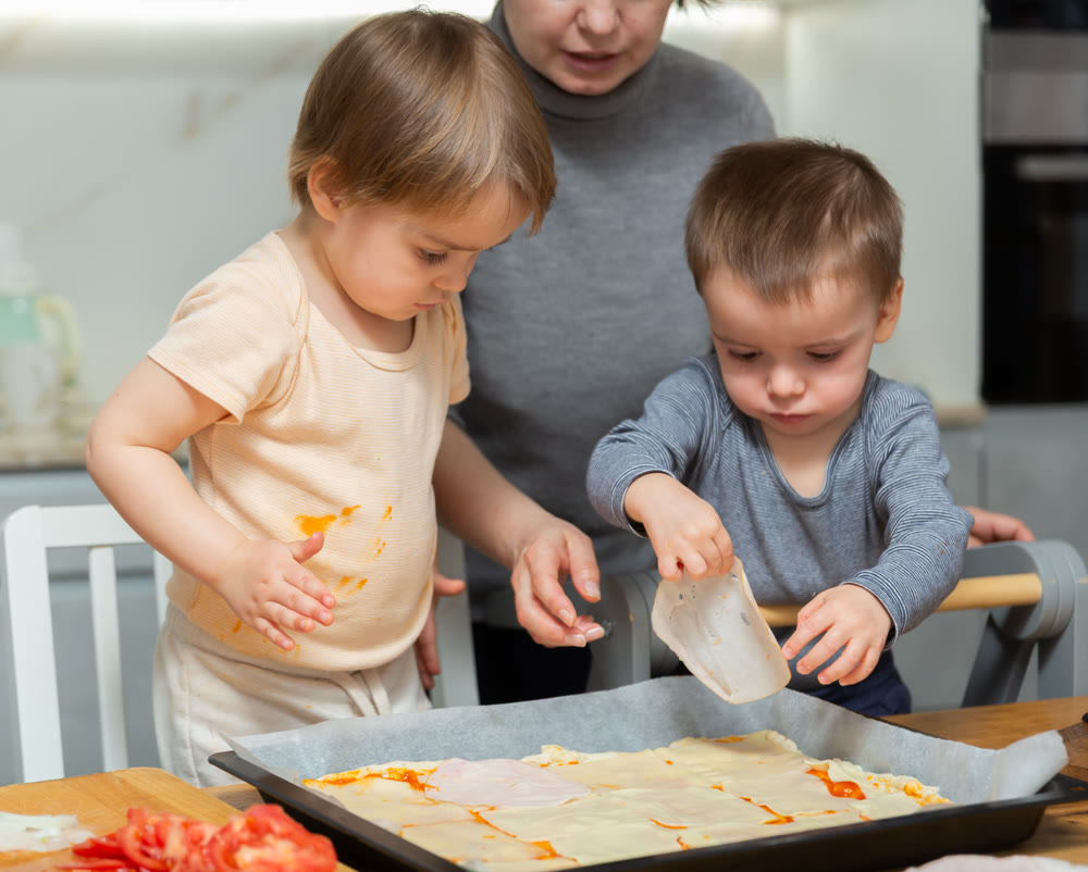 Toddler children help mom cook pizza