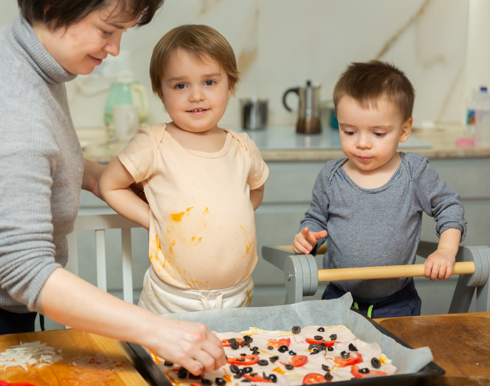 Toddler children help mom cook pizza