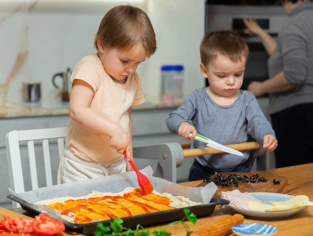 Toddler children help mom cook pizza