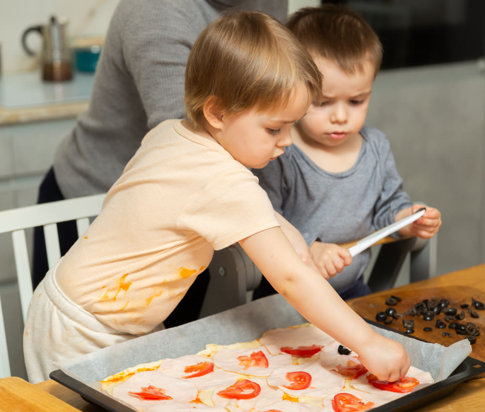 Toddler children help mom cook pizza