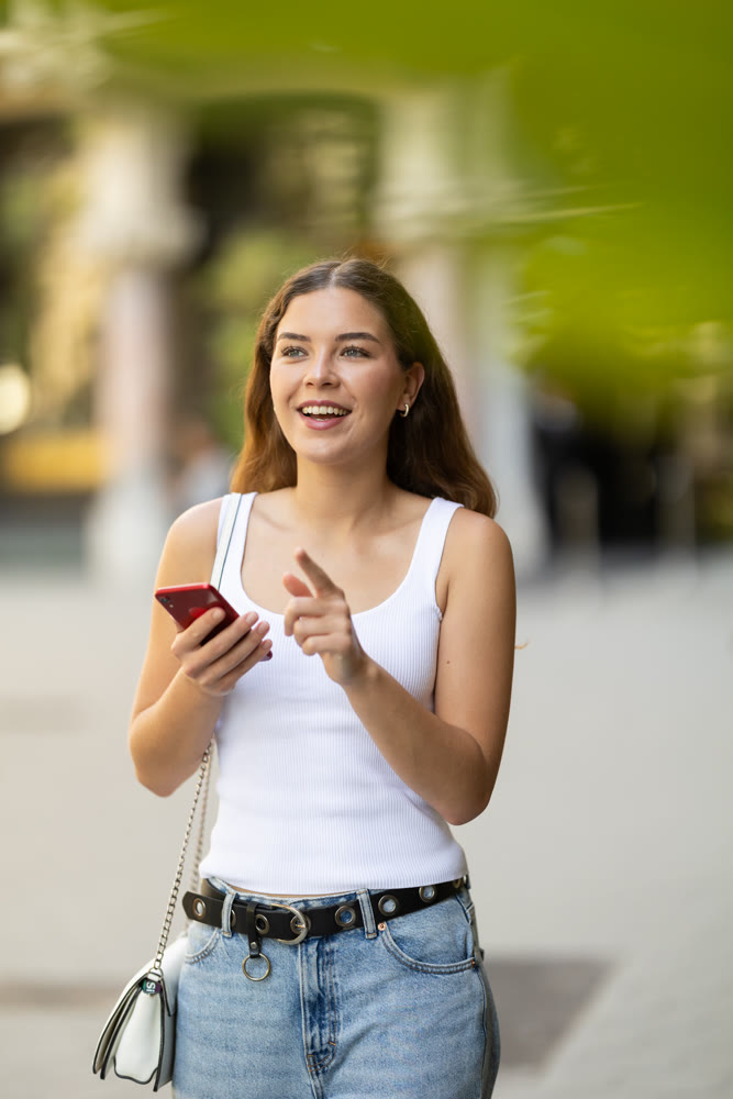 Young girl with mobile phone in her hands walking around the city and taking pictures of sights