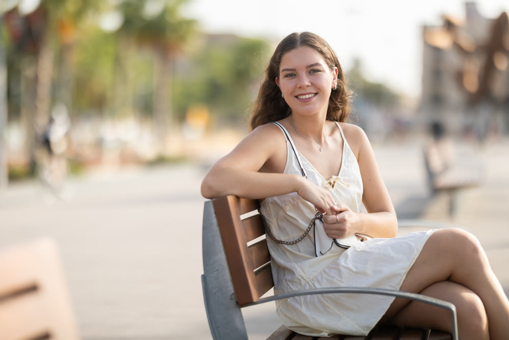 Portrait of girl relaxing on bench in summer city park