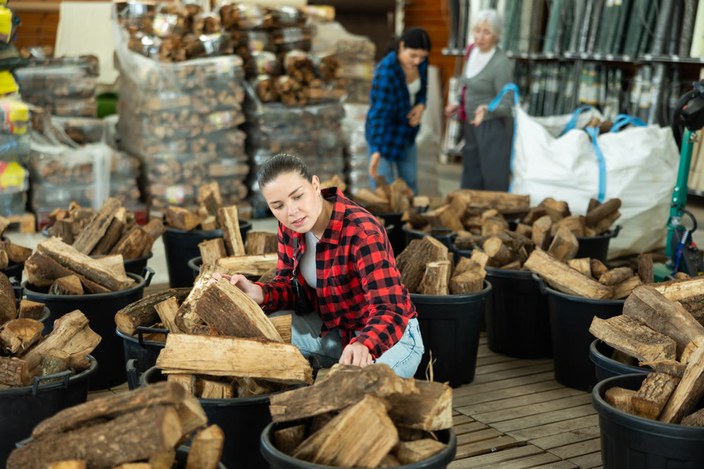 Girl chooses and buys a bundle of firewood at hardware store.