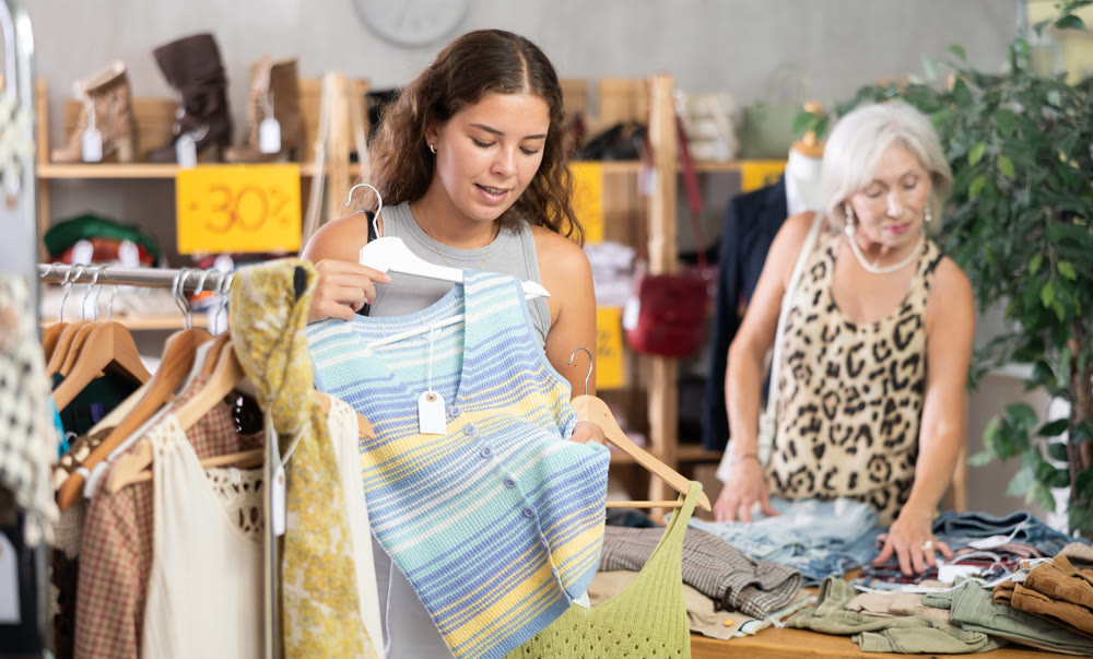 Positive young woman choosing something for summer in clothing store