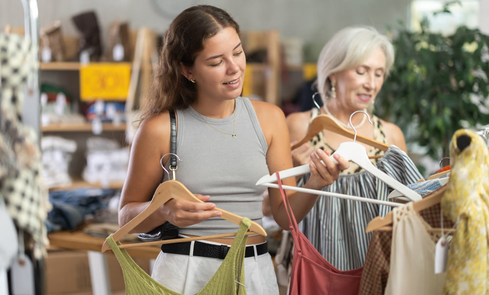 Two happy women of different ages choose summer clothes in fashion boutique