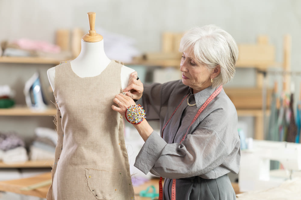 Mature female dressmaker working with mannequin in sewing workshop