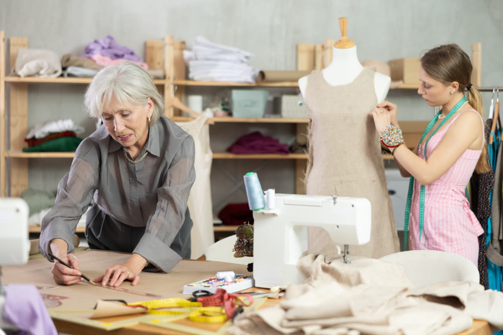 Mature female dressmaker drawing on paper other work with mannequin