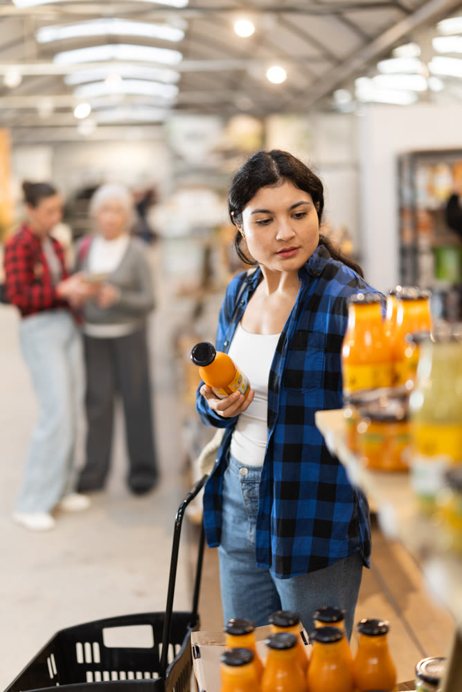 Young woman chooses juice in grocery store