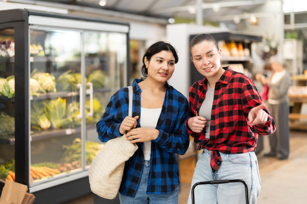 Two young women talk and choosing food in grocery store