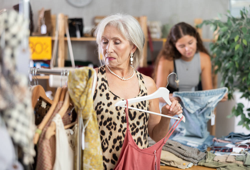 Woman chooses set of clothes for the summer. Visitor to the boutique examines new summer collection of clothes