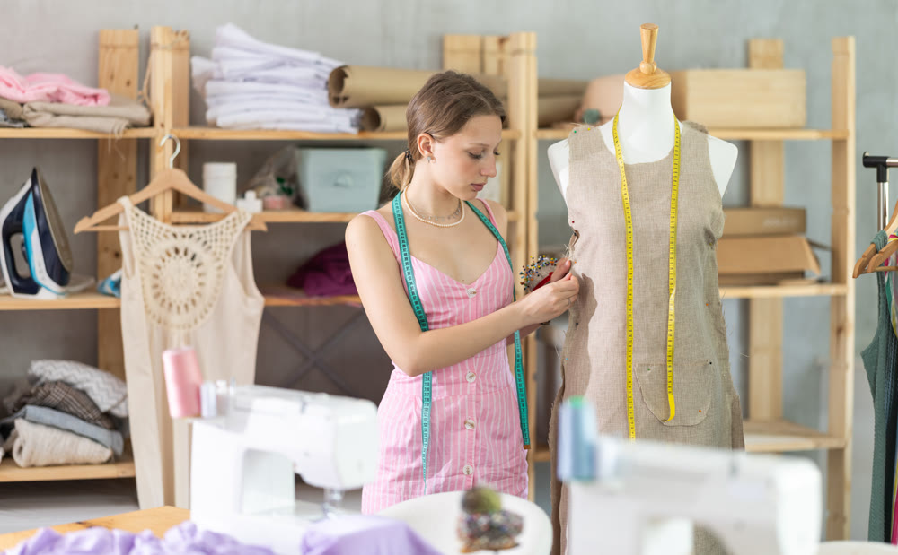 Designer in dress standing near mannequin in workshop