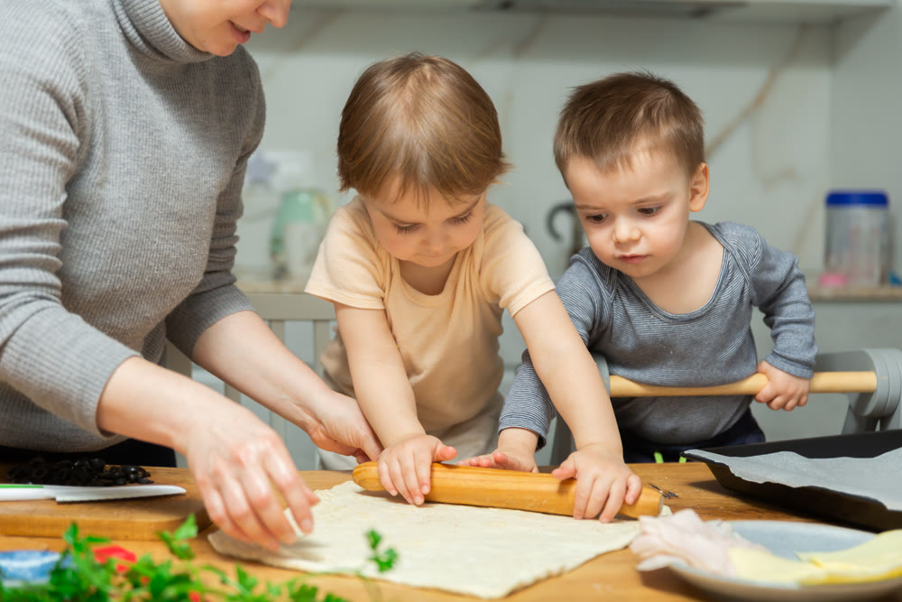 Toddler children help mom cook pizza