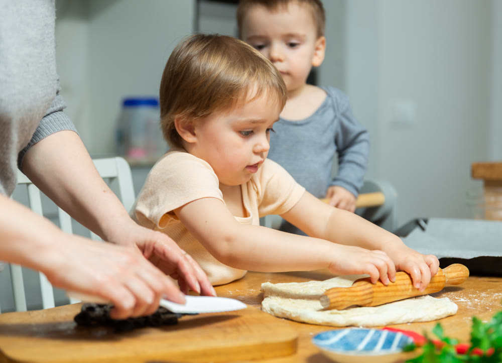 Toddler children help mom cook pizza