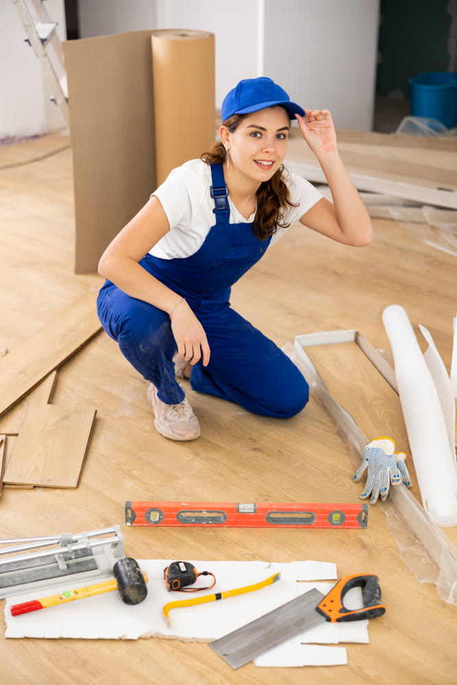 Woman construction worker setting wooden laminate board on floor