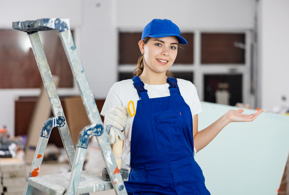 Smiling woman repairer standing inside apartment